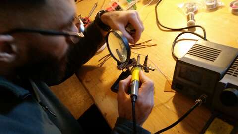 Bränn inte fingrarna! Närbild på en deltagare som löder ihop två kablar med hjälp av förstoringsglas